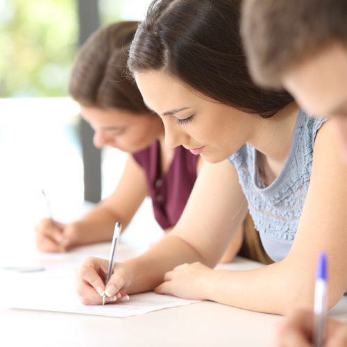 Close up of three concentrated students doing an exam in a classroom