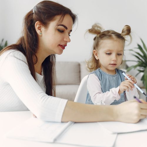 Tutor with pupil. Little girl studying. Private lesson. Mother helps her daughter.